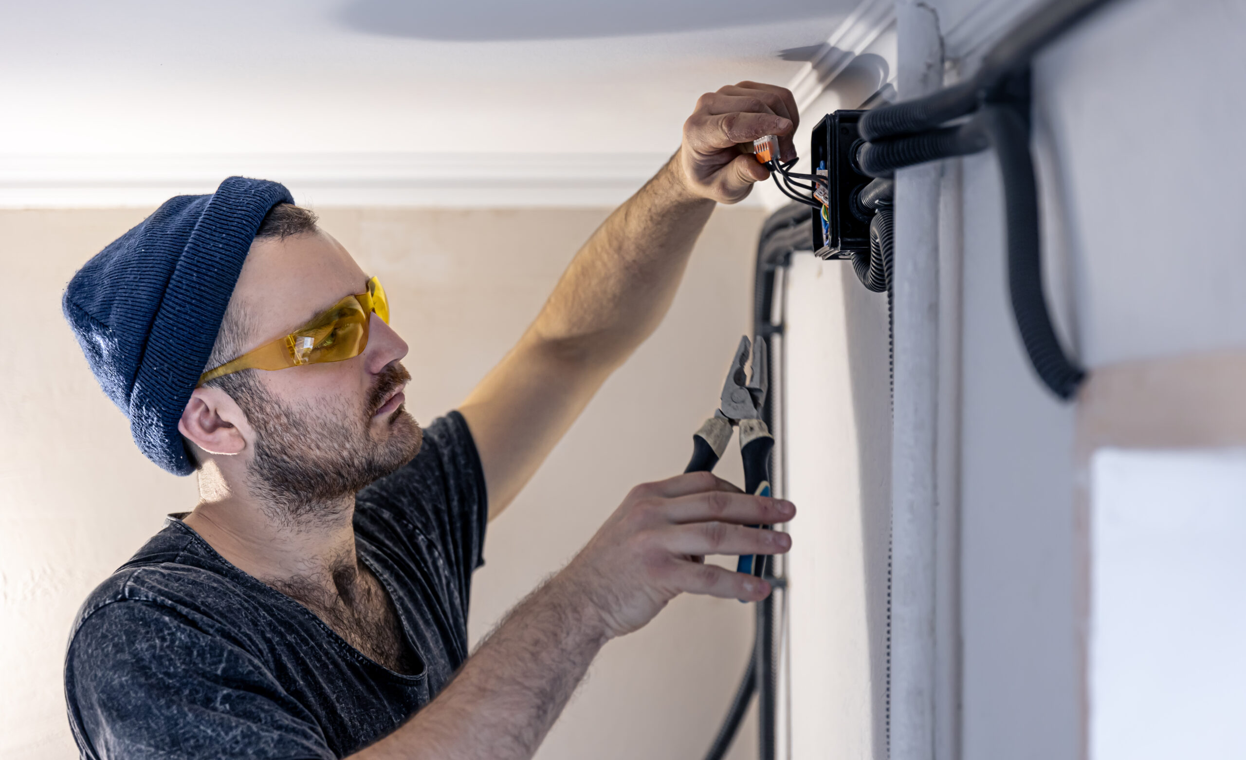 An electrician is mounting electric sockets on the white wall indoors.